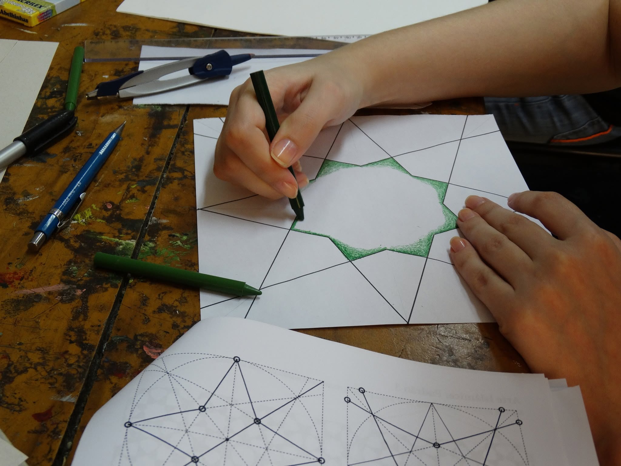 Estudante colorindo uma construção geométrica em papel